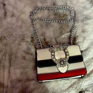 This is a white shoulder bag with 2 strips colored black and red